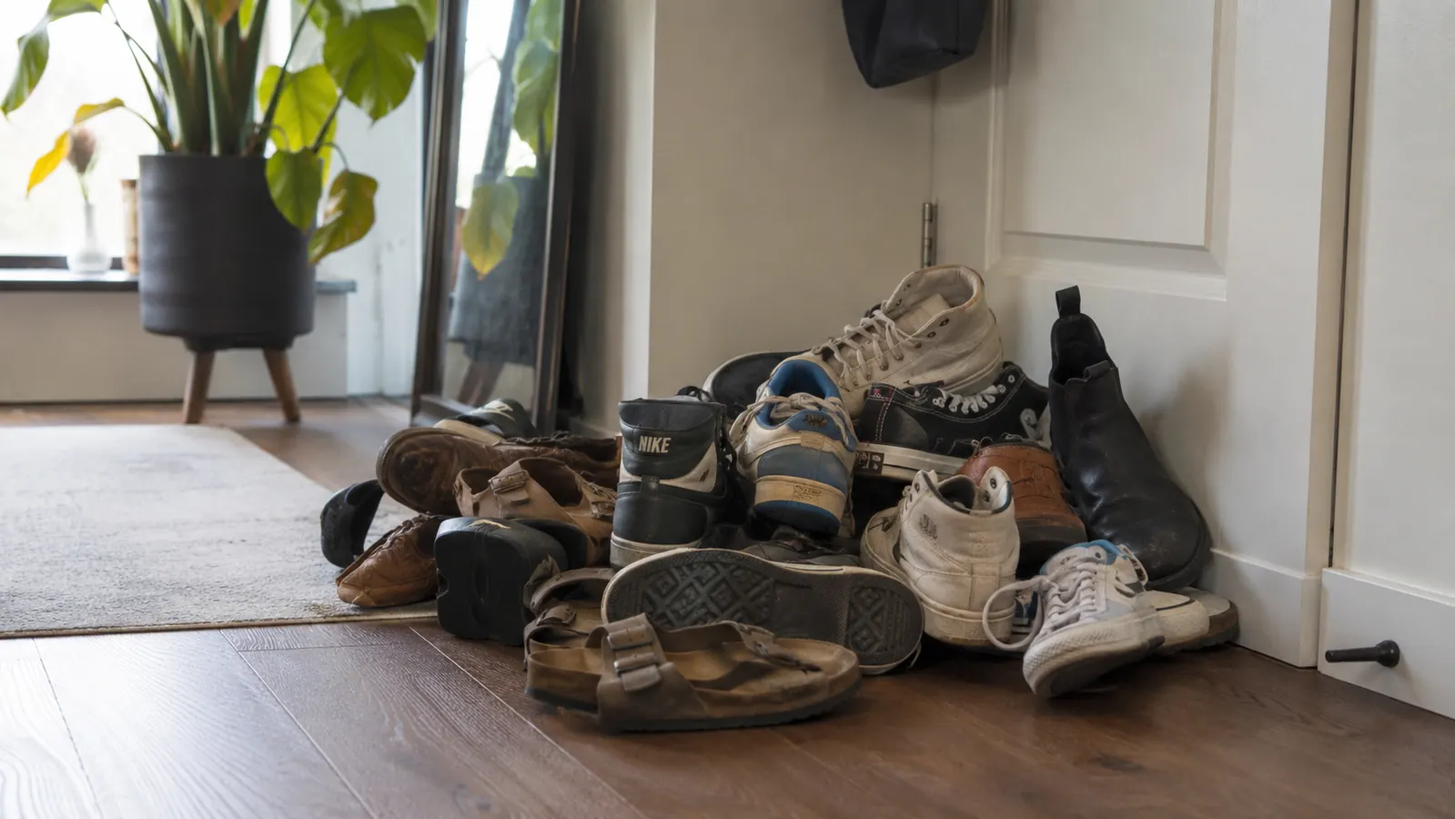 Cluttered apartment entryway with shoes piled on the floor next to a front door